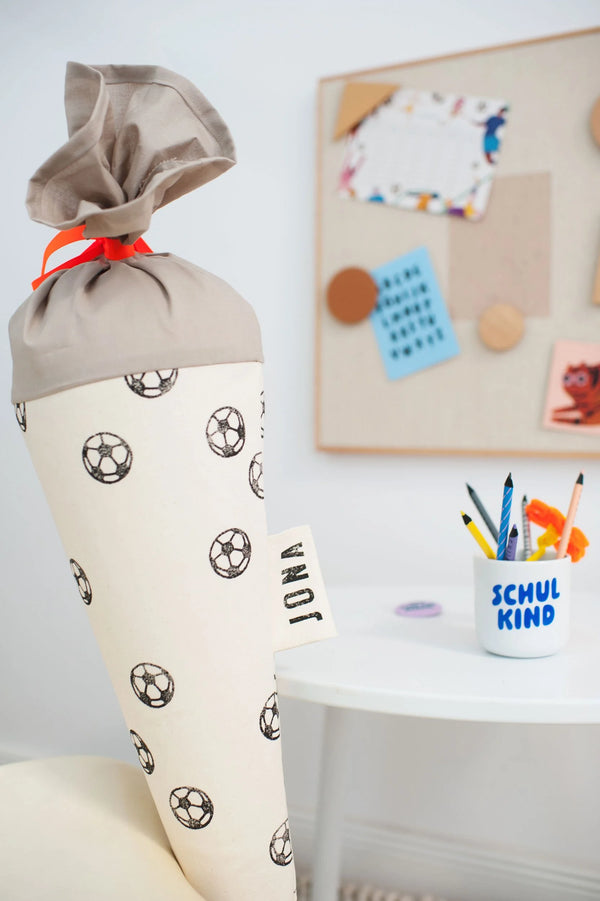 Schultüte aus Stoff mit Fußball-Motiv zur Einschulung mit einem Schulkind-Becher