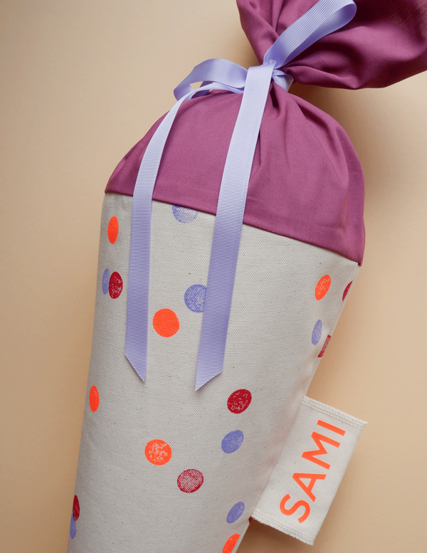 Schultüte aus Stoff mit rotem Konfetti-Motiv und seitlichem Namenslabel